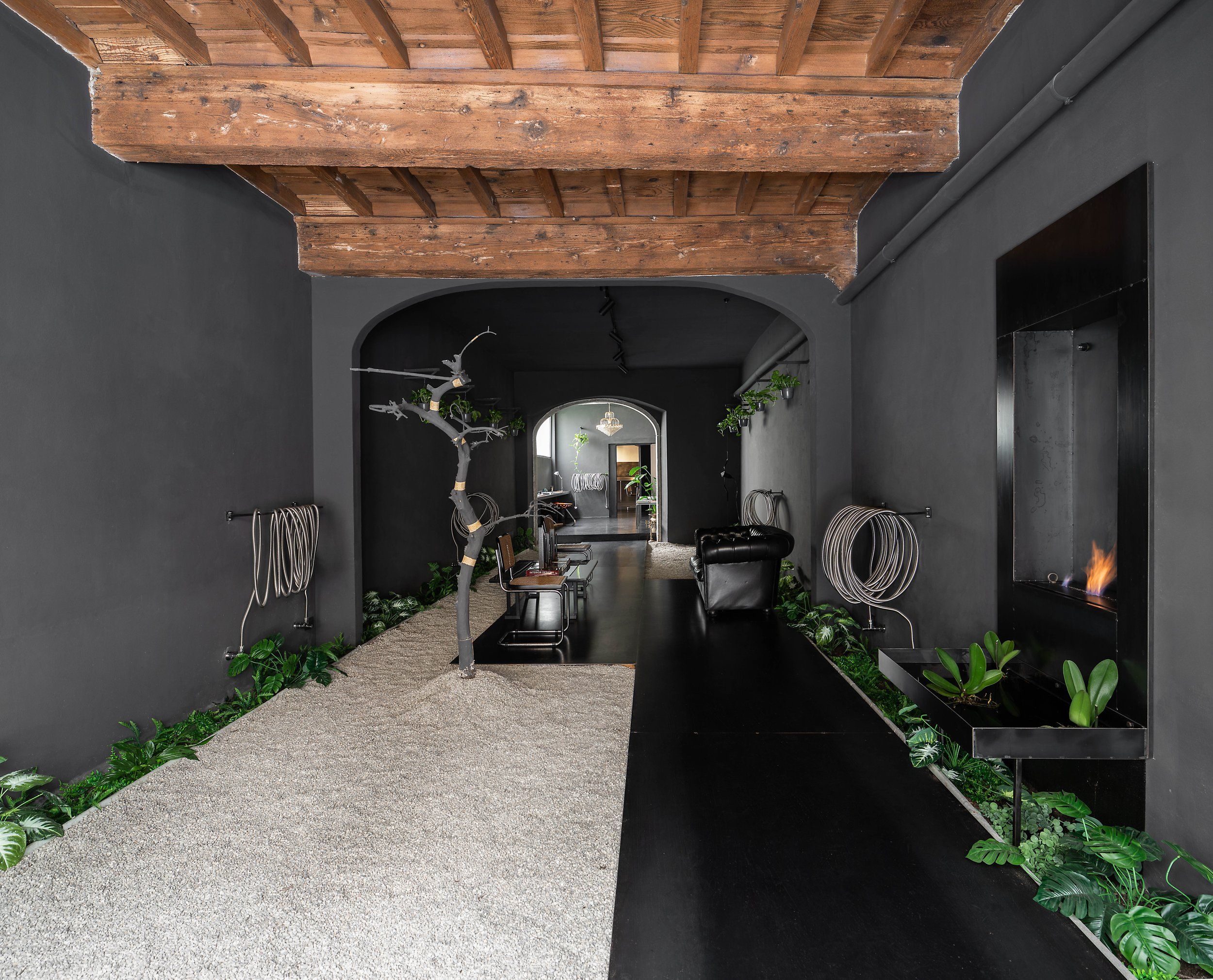 The entrance of the 28nero atelier, with the blackened olive trunk and the iron bio-fireplace