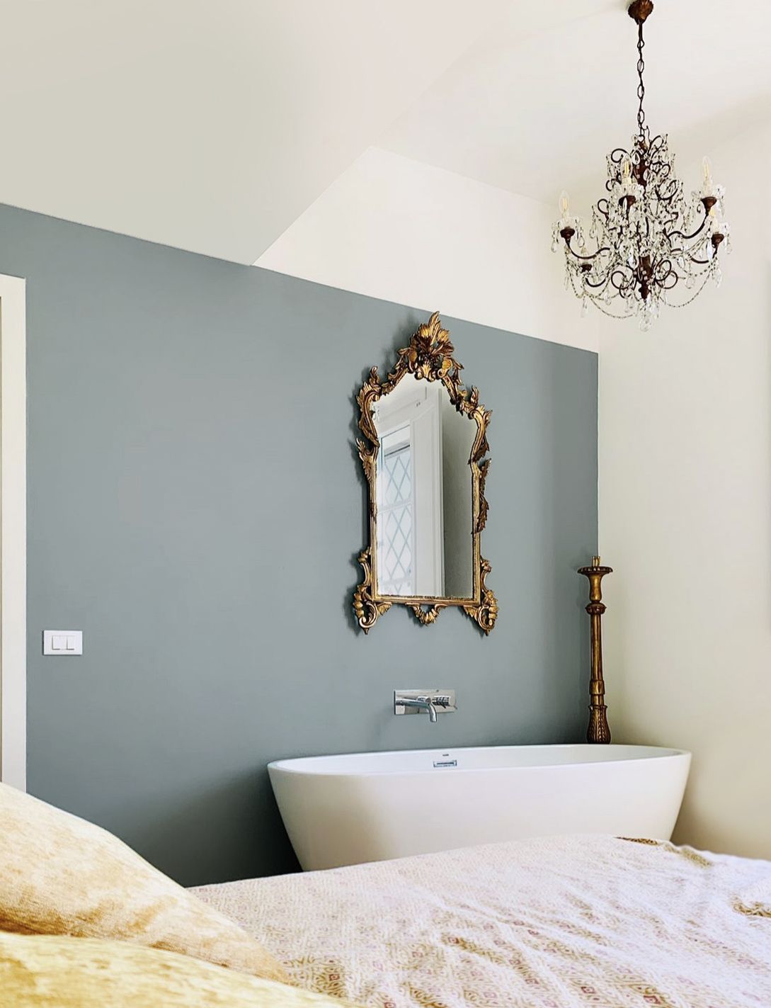 A freestanding bathtub at the foot of the bed