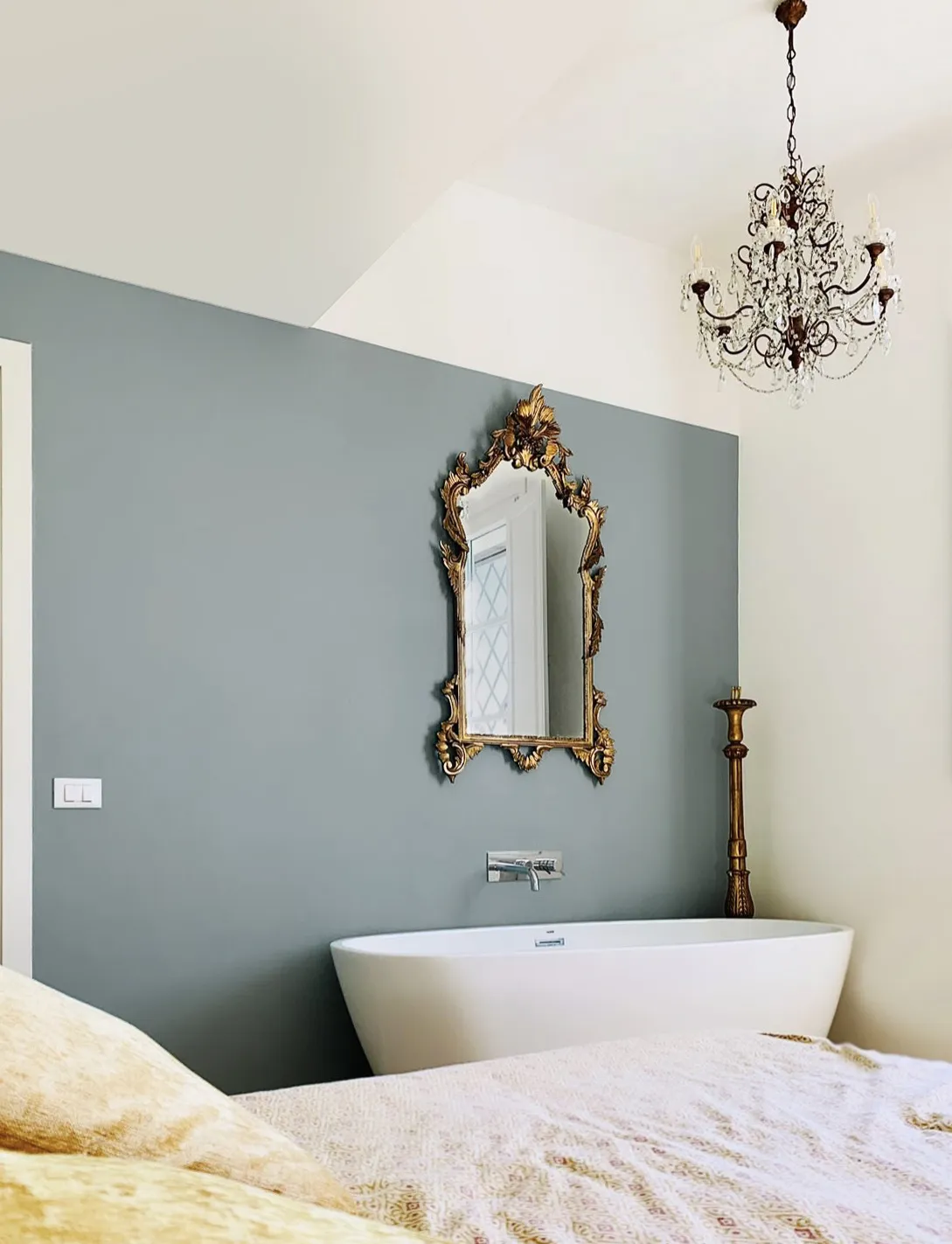 A freestanding bathtub at the foot of the bed