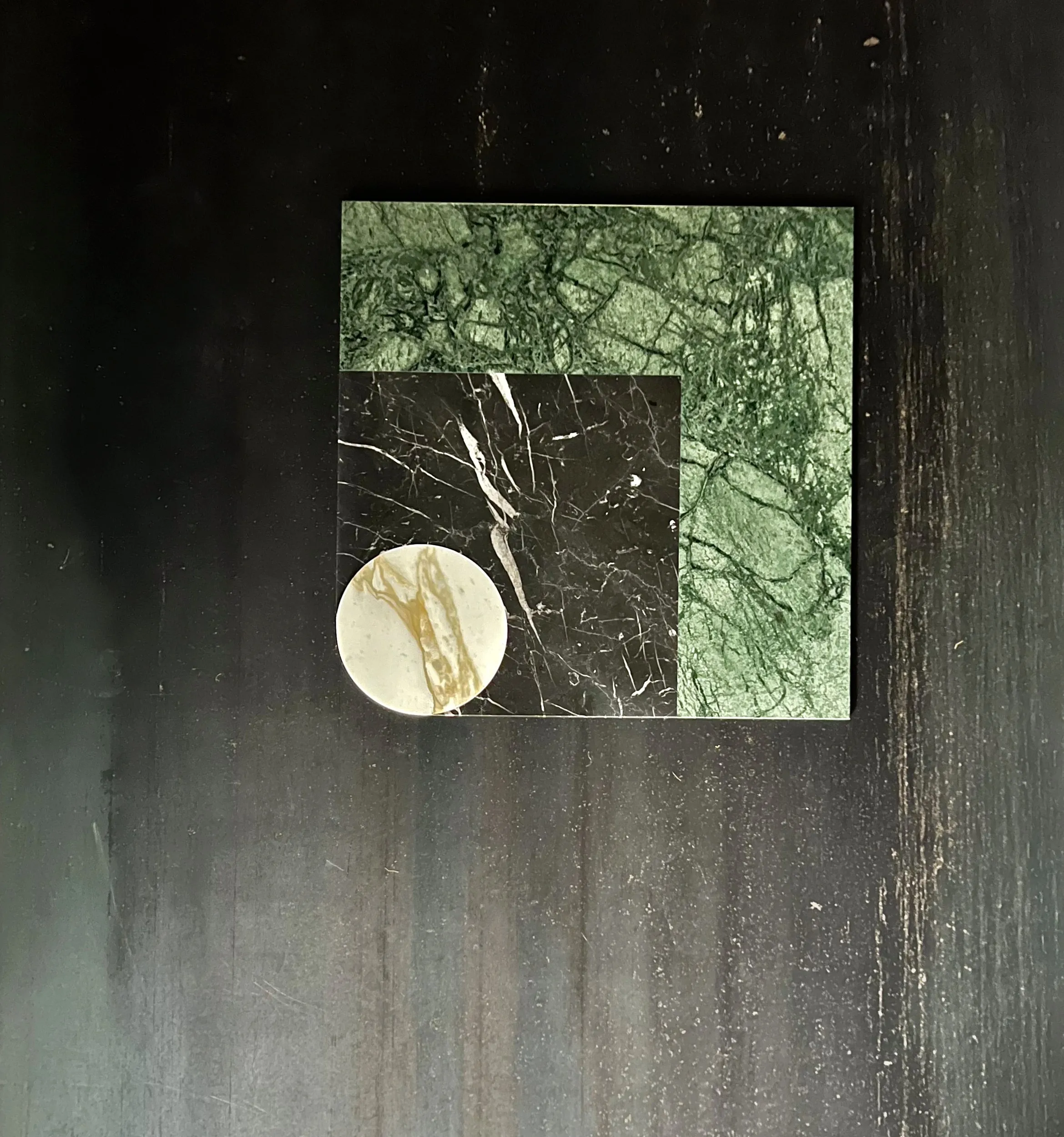 Chimera marbles on a dark wall: green, black and a white disc