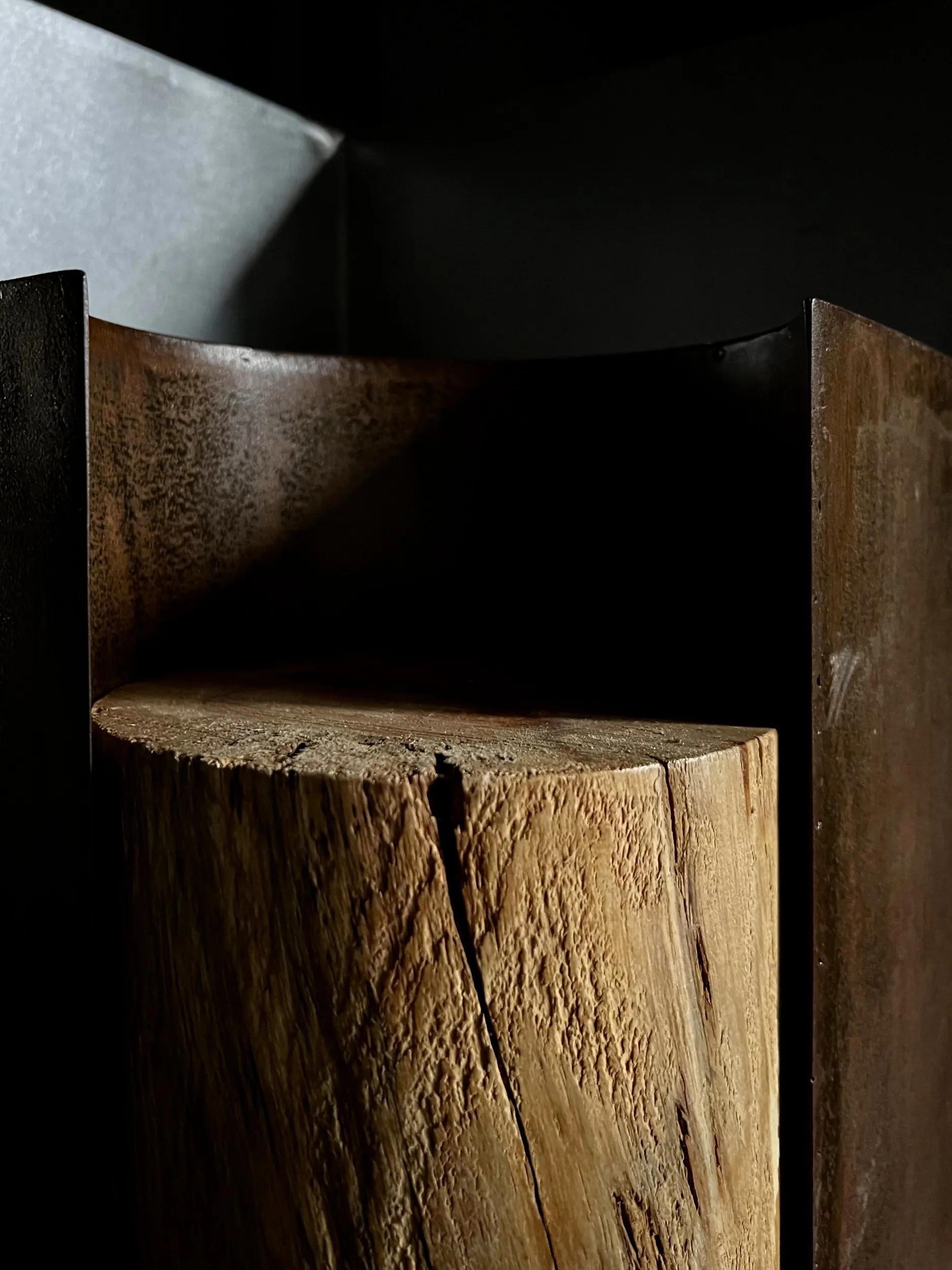 A block of wood set inside the oxidised iron shell of a Chimera bedside table