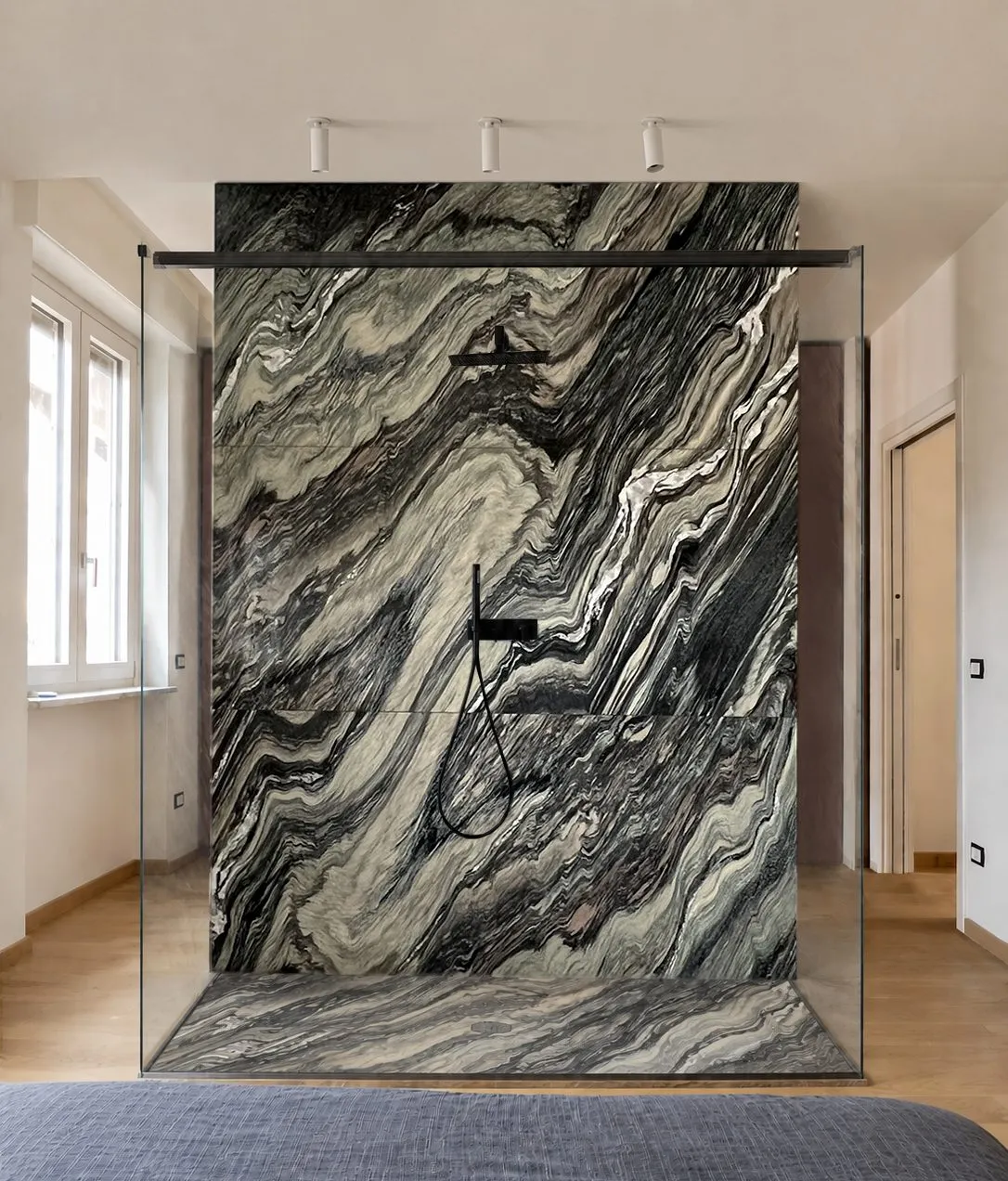 A marble-clad shower standing free in the bedroom, black fixtures