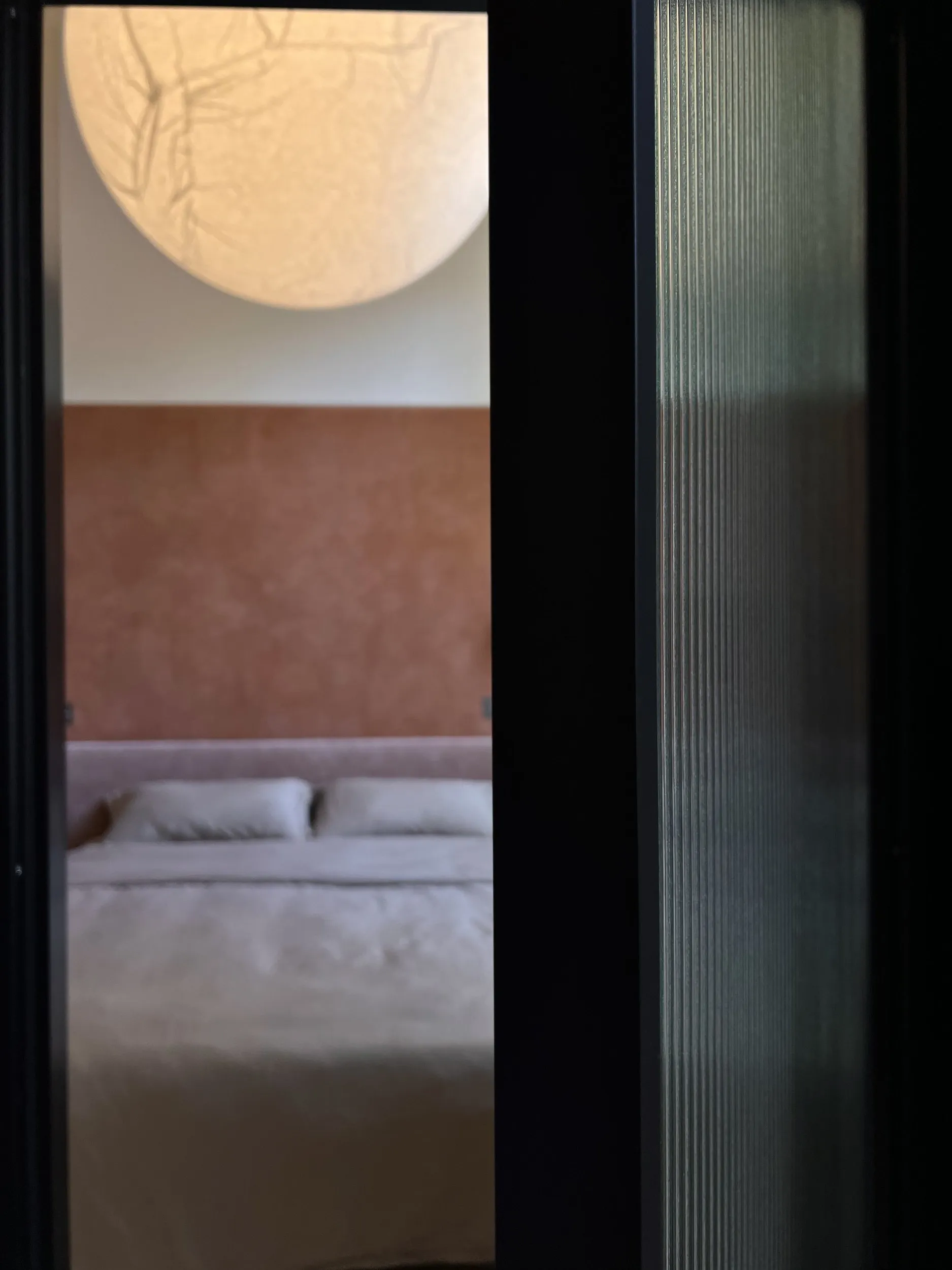 A black frame in fluted glass, a bedroom glimpsed beyond