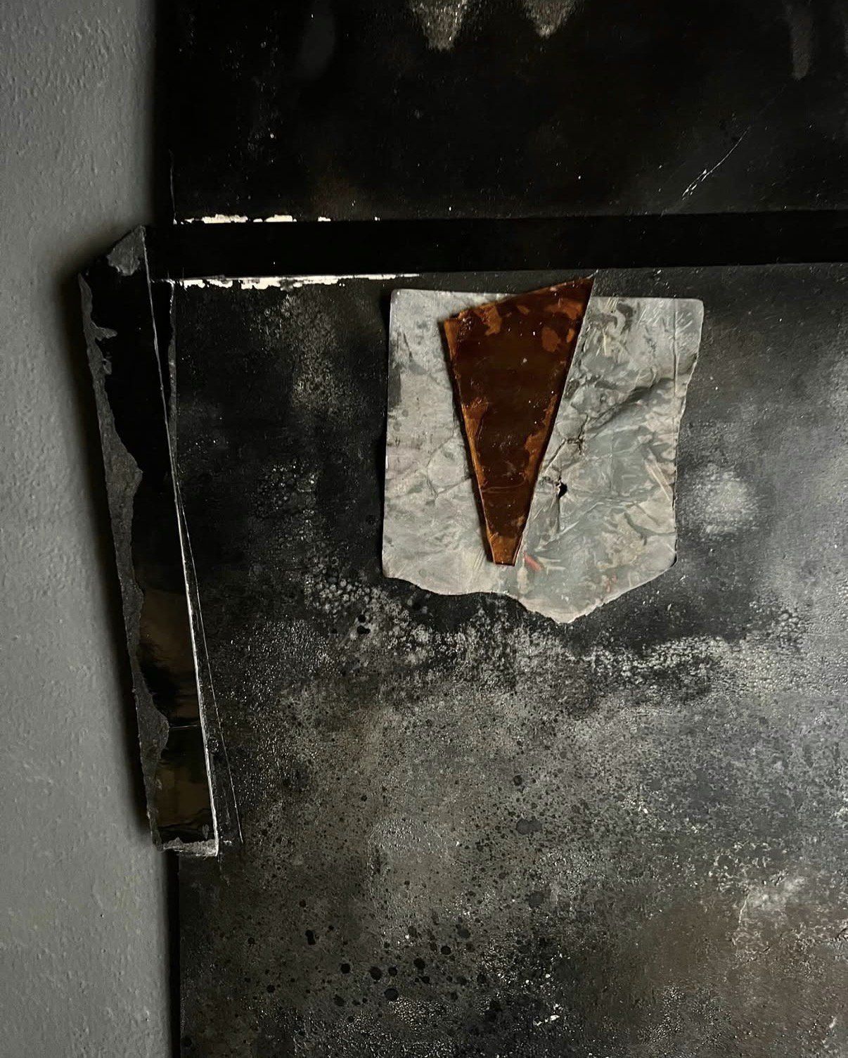 A dark artwork hung on the dark wall of the atelier